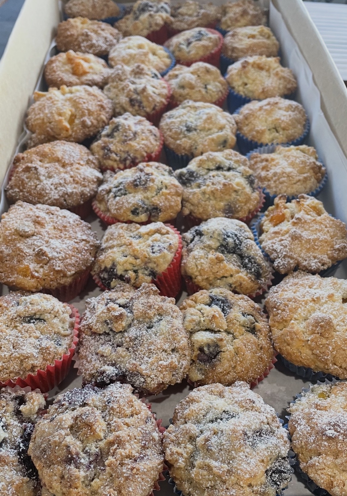 A catering box filled with freshly baked muffins