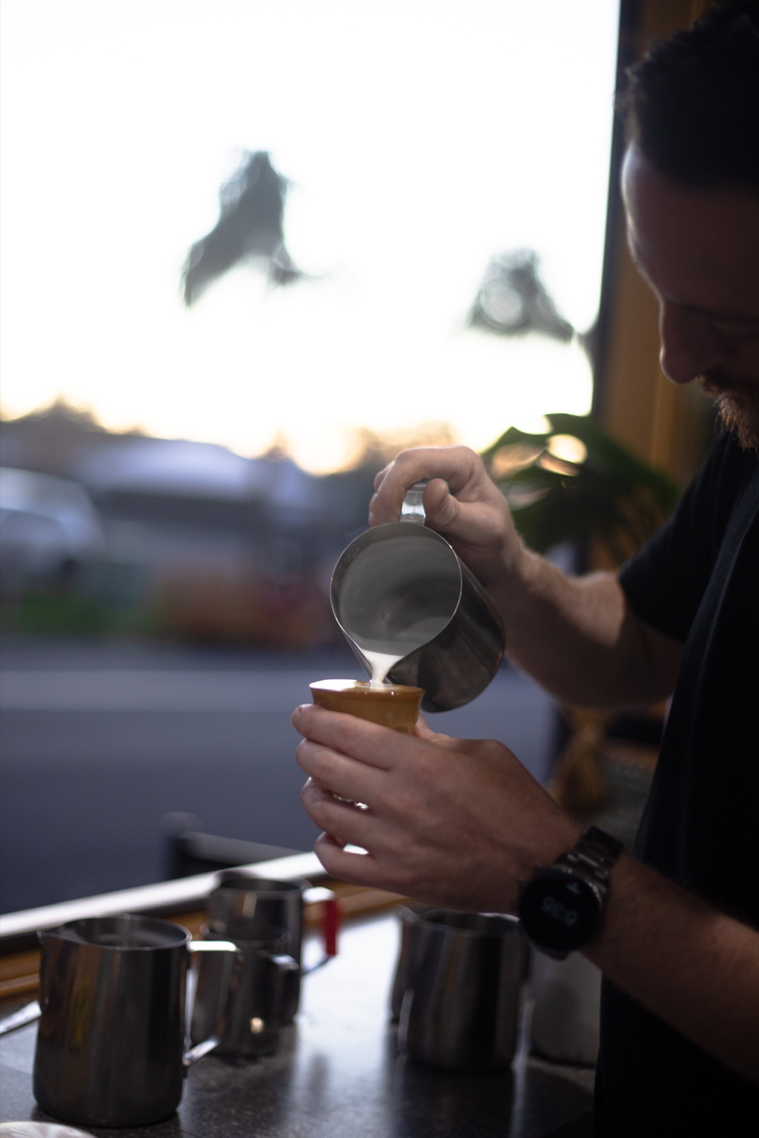 Blackbird barista pouring steamed milk into a coffee